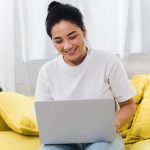 atinatin-smiley-woman-home-couch-with-laptop_23-2148655922