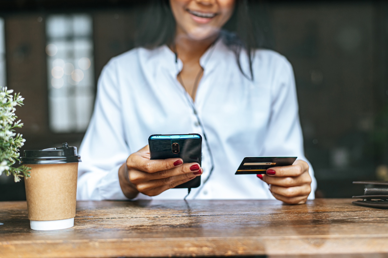 Pay for goods by credit card through a smartphone in a coffee shop.