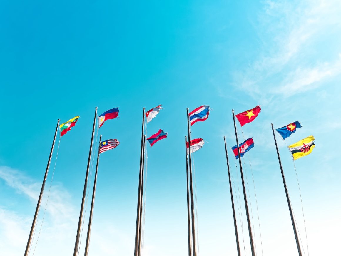 Low Angle View of Waving Flags of ASEAN Countries Against Blue Sky